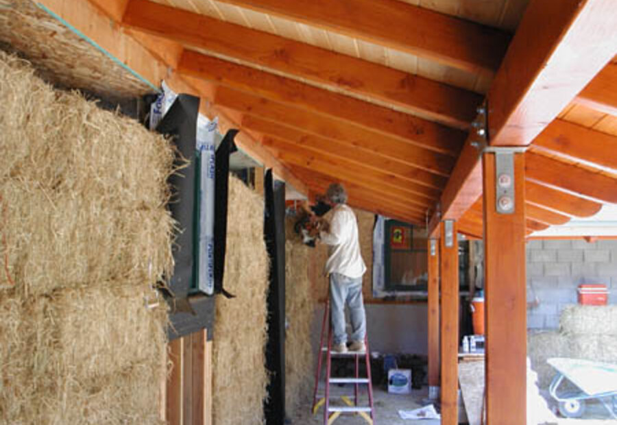 Straw bale wall construction inside a timber-framed building